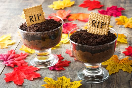 Funny Halloween chocolate mousse with tomb cookie on wooden table