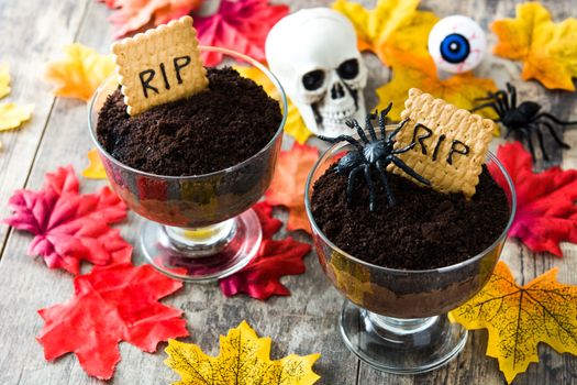 Funny Halloween chocolate mousse with tomb cookie on wooden table