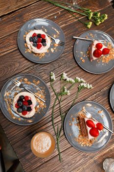 Bachelorette party, girls hands with drinks and sweet cakes with summer berries on a wooden table. Party, sweet table. Summer offer desserts in the restaurant