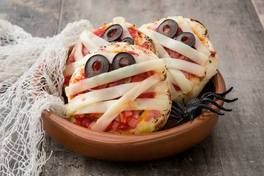 Halloween mummies mini pizzas on wooden table.