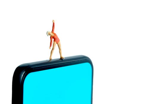 Yoga trainer app. A women doing exercise above smartphone. Miniature people figure conceptual photography.