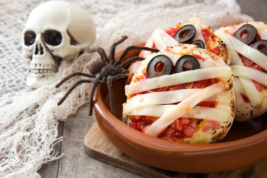 Halloween mummies mini pizzas on wooden table.