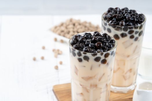 Bubble milk tea with tapioca pearl topping ingredient, famous Taiwanese drink on white wooden table background in drinking glass, close up, copy space