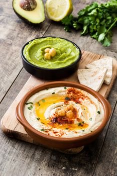 Different hummus bowls. Chickpea hummus, avocado hummus and lentils hummus on wooden table