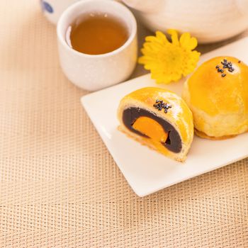 Tasty baked egg yolk pastry moon cake for Mid-Autumn Festival on bright wooden table background. Chinese festive food concept, close up, copy space.