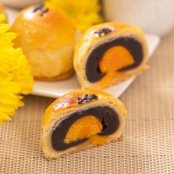 Tasty baked egg yolk pastry moon cake for Mid-Autumn Festival on bright wooden table background. Chinese festive food concept, close up, copy space.