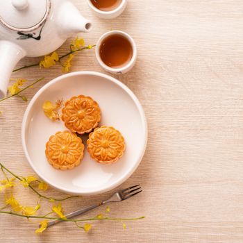 Mid-Autumn Festival holiday concept design of moon cake, mooncakes, tea set on bright wooden table with copy space, top view, flat lay, overhead shot