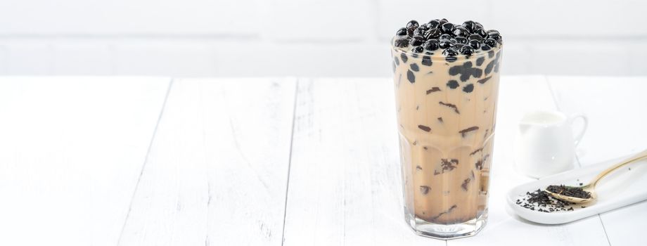 Bubble milk tea with tapioca pearl topping, famous Taiwanese drink on white wooden table background in drinking glass, close up, copy space