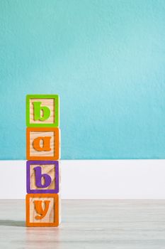 Wooden cubes with letters with "baby" word on white wooden table. Copyspace.