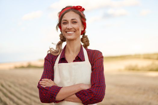 Woman farmer apron standing farmland smiling Female agronomist specialist farming agribusiness Happy positive caucasian worker agricultural field Pretty girl arms crossed dressed red checkered shirt