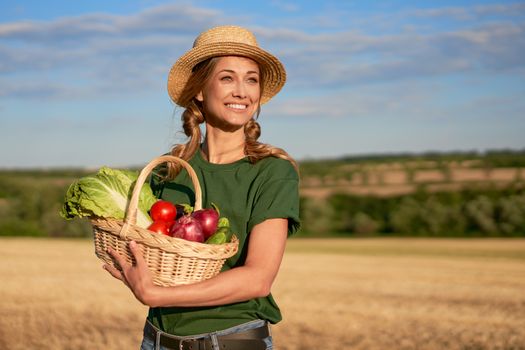 Woman farmer straw hat holding basket vegetable onion tomato salad cucumber standing farmland smiling Female agronomist specialist farming agribusiness