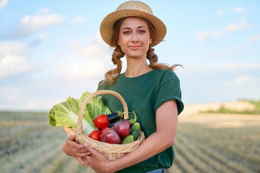 Woman farmer straw hat holding basket vegetable onion tomato salad cucumber standing farmland smiling Female agronomist specialist farming agribusiness