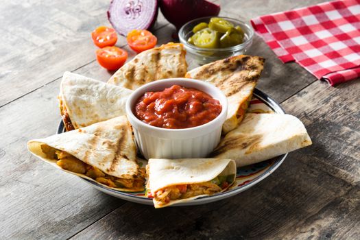 Mexican quesadilla with chicken, cheese and peppers on wooden table.