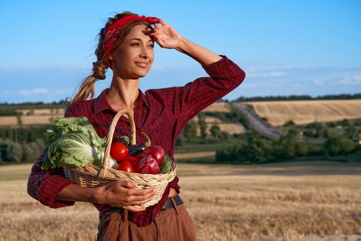 Woman farmer holding basket vegetable onion tomato salad cucumber standing farmland smiling Female agronomist specialist farming agribusiness Pretty girl dressed red checkered shirt and bandana