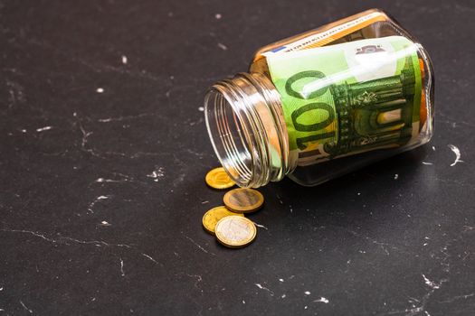 Composition with saving money banknotes in a glass jar. Concept of investing and keeping money, close up isolated.