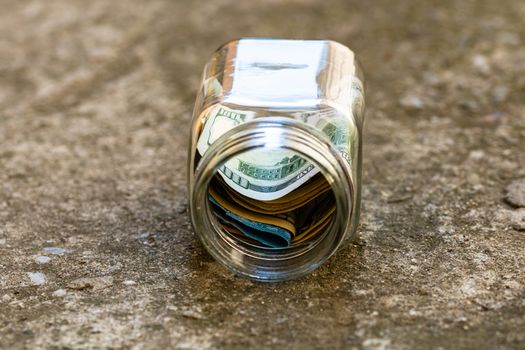 Composition with saving money banknotes in a glass jar. Concept of investing and keeping money, close up isolated.