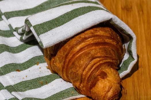 Detail of fresh croissant on wooden table. Food and breakfast concept. Close up photo of French buttery croissant