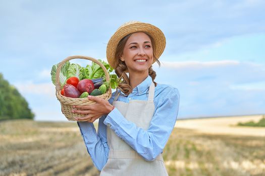 Woman farmer straw hat holding basket vegetable onion tomato salad cucumber standing farmland smiling Female agronomist specialist farming agribusiness Happy Girl dressed apron cultivated wheat field