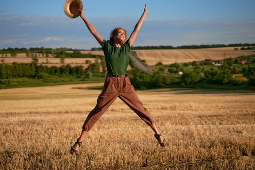 Woman farmer straw hat standing farmland smiling Female agronomist specialist farming agribusiness Happy positive caucasian worker agricultural field Pretty girl denim jeans green t-shirt harvest jump
