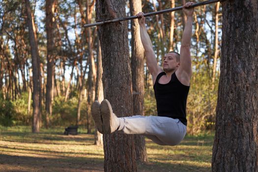 Handsome caucasian men pull-up outdoor workout cross training morning Pumping arm abdominal exercising sports ground nature forest Healthy lifestyle Young adult male fit body DIY horizontal bar