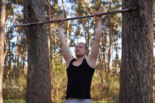 Handsome caucasian men pull-up outdoor workout cross training morning Pumping arm exercising sports ground nature forest Healthy lifestyle Young adult male fit body Cross training DIY horizontal bar