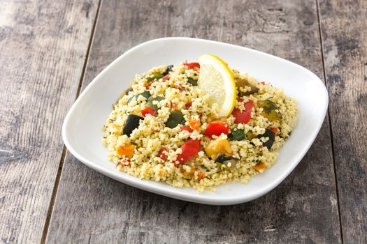 Couscous with vegetables on wooden table