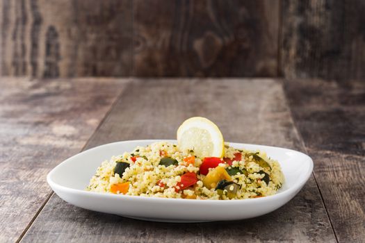 Couscous with vegetables on wooden table