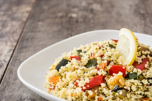 Couscous with vegetables on wooden table