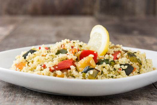 Couscous with vegetables on wooden table