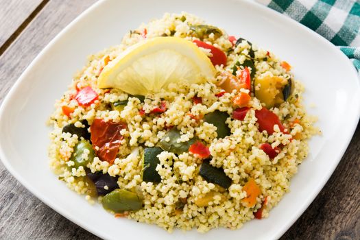 Couscous with vegetables on wooden table