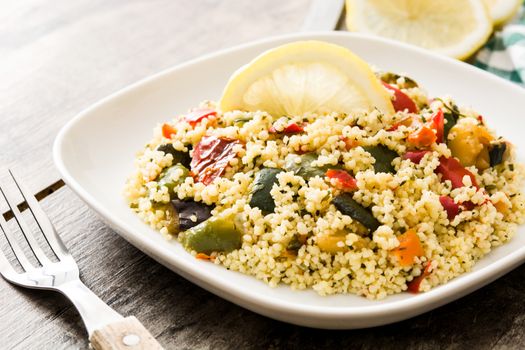 Couscous with vegetables on wooden table