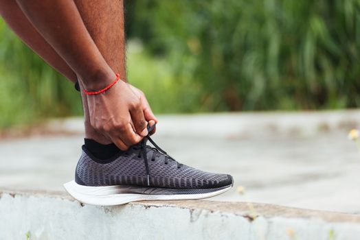 Close up Asian sport runner black man wear watch stand step on the footpath trying shoelace running shoes getting ready for jogging and run outdoor street health park, healthy exercise workout concept