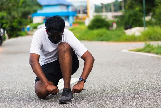 Close up Asian sport runner black man wear watch sitting he trying shoelace running shoes getting ready for jogging and run outdoor street health park with copy space, healthy exercise workout concept