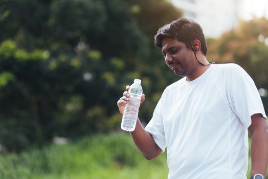 Close up Asian young sport runner black man wear athlete headphones he drinking water from a bottle after running at the outdoor street health park, healthy exercise workout concept