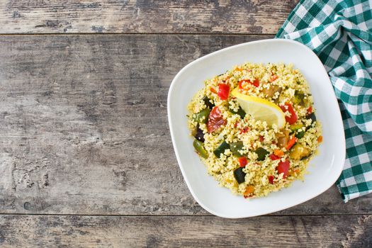 Couscous with vegetables on wooden table