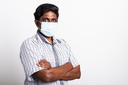 Closeup Asian handsome black man wearing surgical hygienic protective cloth face mask against coronavirus and stand crossed arm, studio shot isolated white background, COVID-19 medical concept