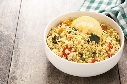 Couscous with vegetables on wooden table