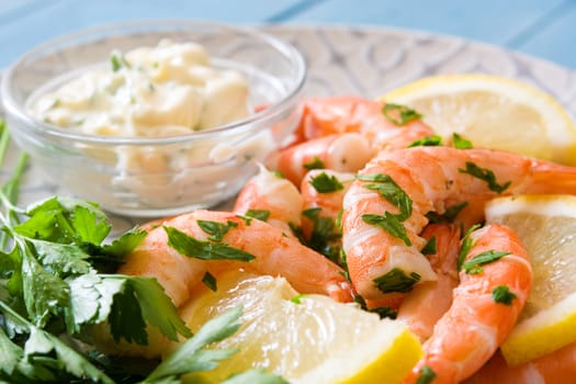 Grilled shrimps, parsley and lemon on blue wooden table