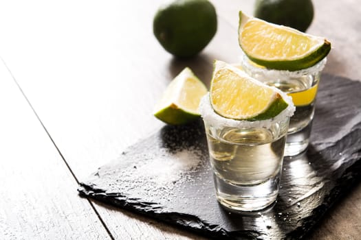 Mexican Gold tequila with lime and salt on wooden table.