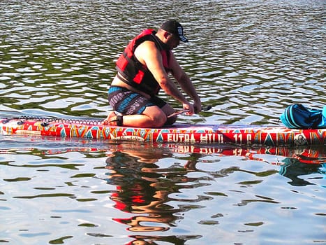 summer, pond, park, young man, a man over 40 sails in a narrow inflatable boat in the afternoon