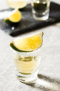 Mexican Gold tequila with lime and salt on gray background