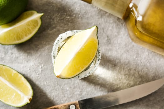 Mexican Gold tequila with lime and salt on gray background