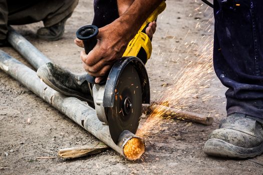 Worker cutting metal pipe outdoor