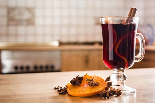 Mulled wine in glass with spice and fruit on wooden table. Copyspace