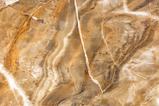 Unusual texture of old brown marble with beige spots, cracks and scratches. Polished surface.