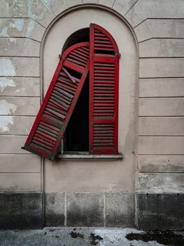 Red doors of a window of an old dilapidated Italian building of the twentieth century, urbex image