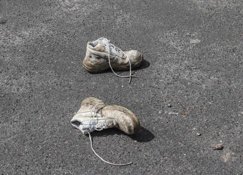 Old shoes with copy space for text left on an ashpalt road. Stylish and fashion accessories - men's wear shoes concept.