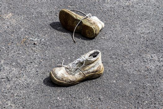 Old shoes with copy space for text left on an ashpalt road. Stylish and fashion accessories - men's wear shoes concept.