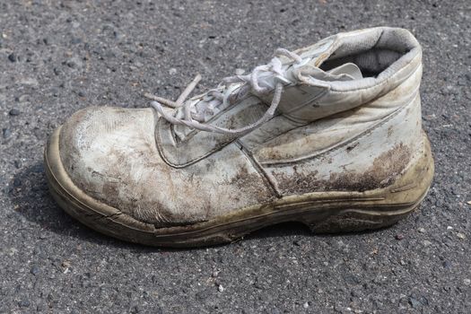 Old shoes with copy space for text left on an ashpalt road. Stylish and fashion accessories - men's wear shoes concept.