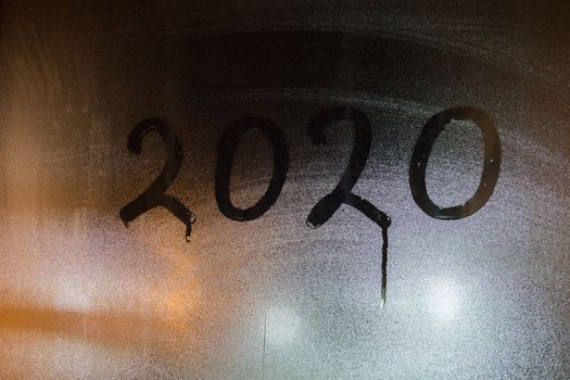 digit 2020 written on night wet window glass close-up.